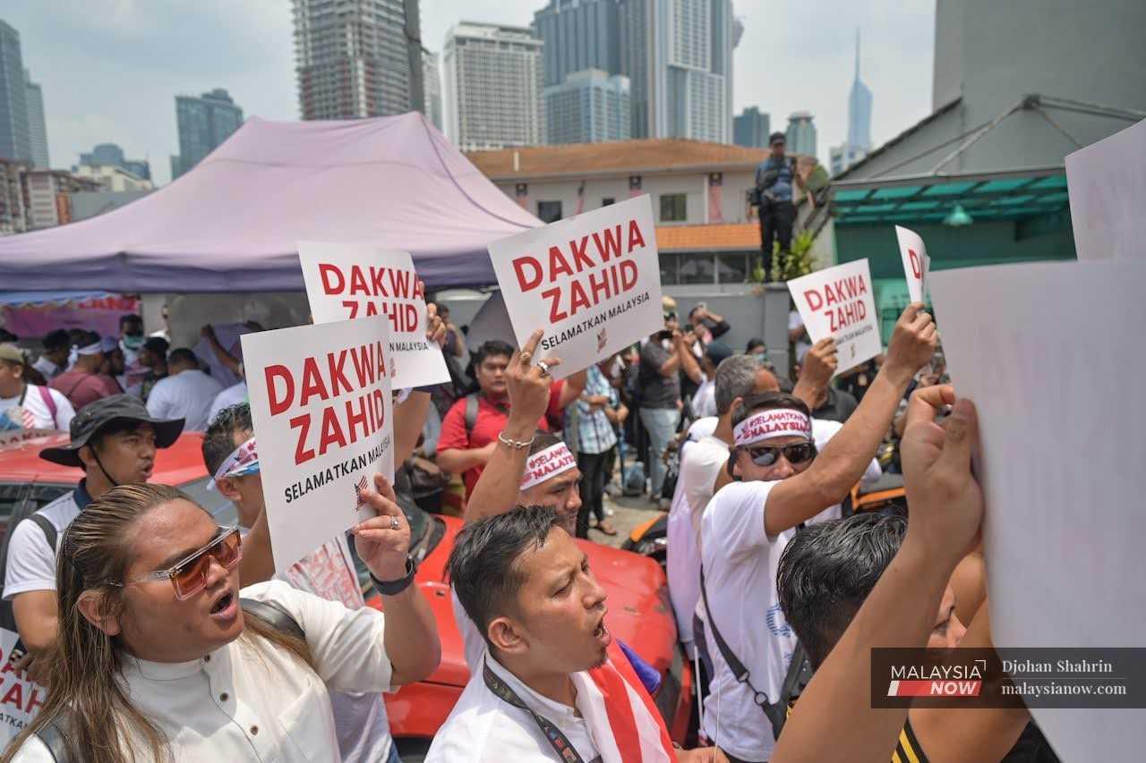 Penunjuk perasaan memegang plakad menggesa Timbalan Perdana Menteri Ahmad Zahid Hamidi didakwa semula pada perhimpunan 'Selamatkan Malaysia' di Kampung Baru, Kuala Lumpur.