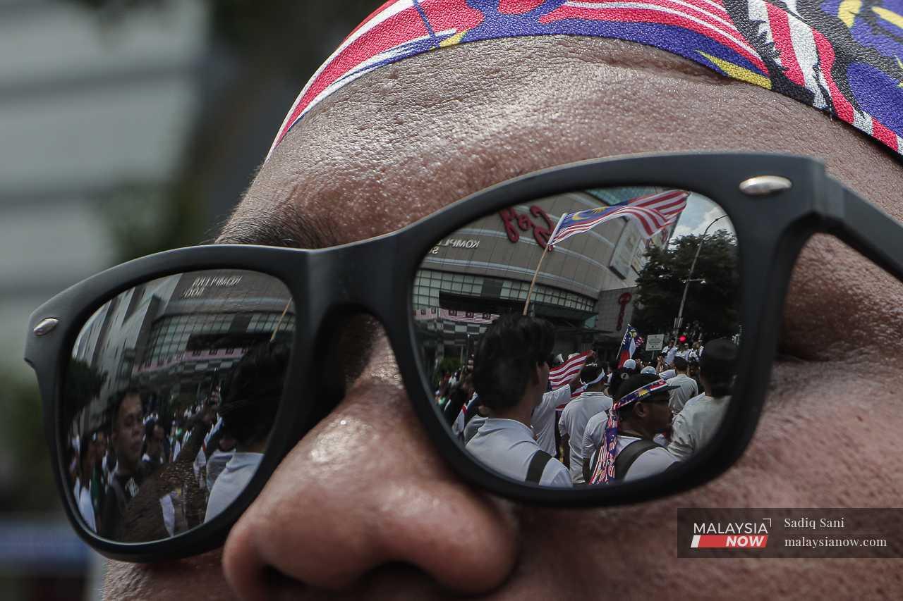 Protesters and flags are reflected in the sunglasses of a participant.