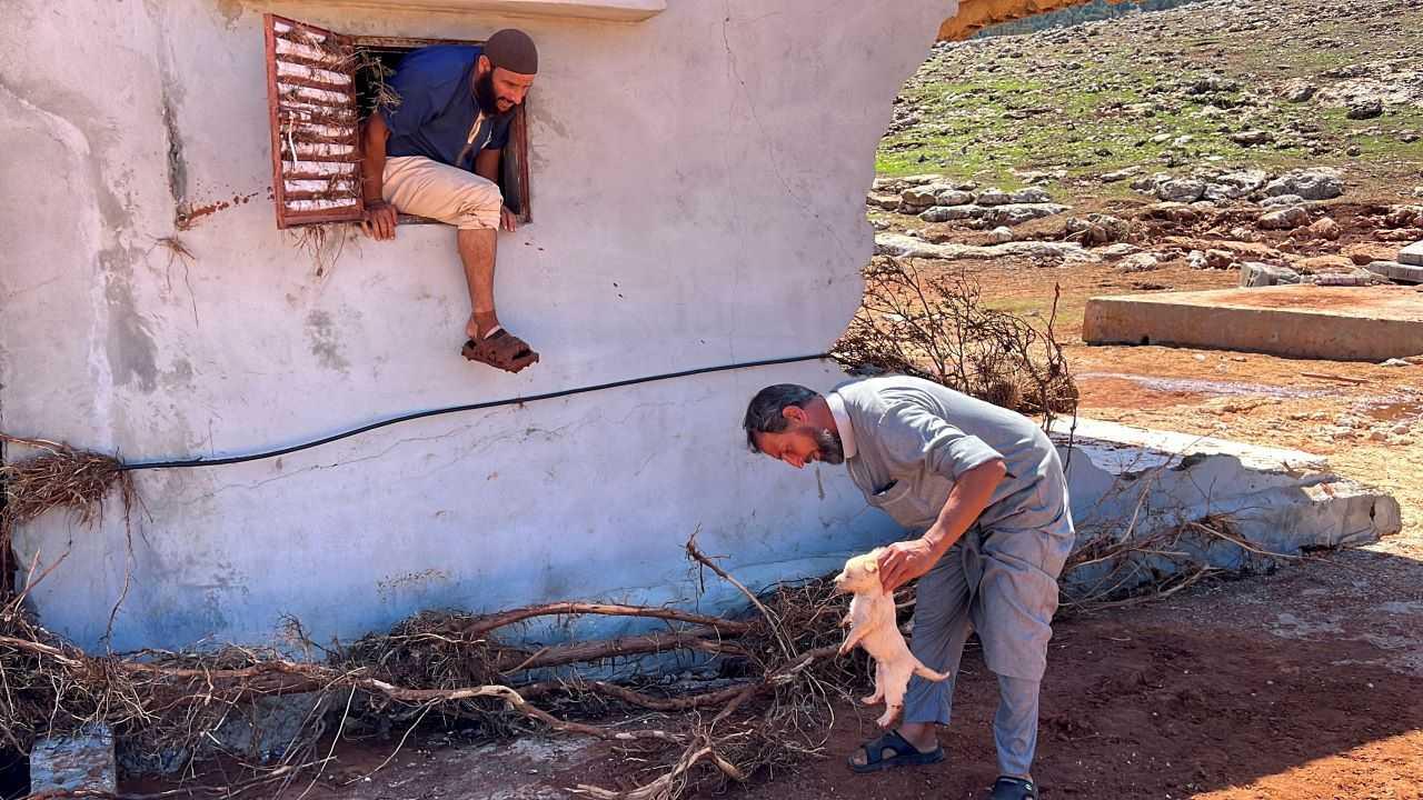 A man carries a dog outside a destroyed house, in the aftermath of the floods in Wadi Al Ahmar, Libya Sept 16. Photo: Reuters