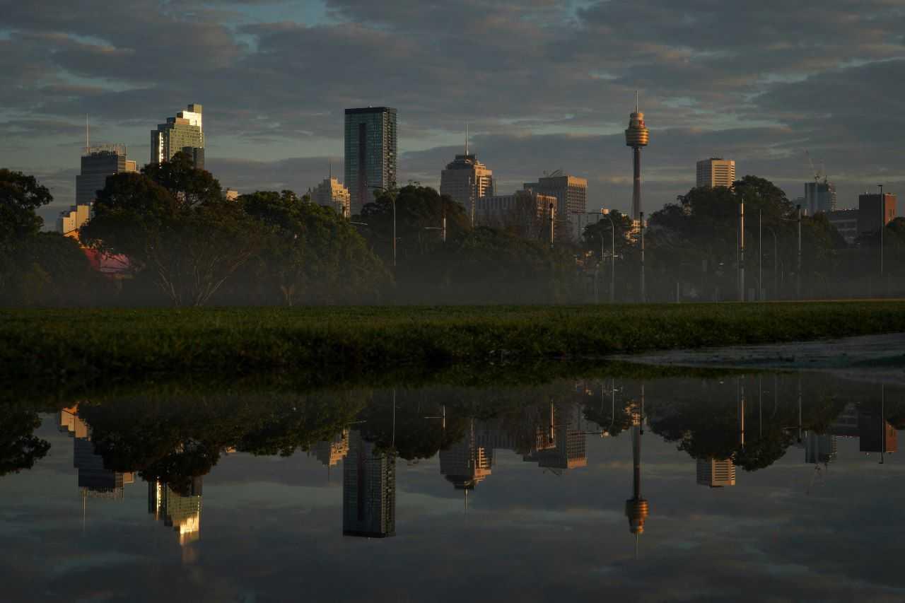 The city skyline is reflected in a puddle at sunrise in Sydney, Australia, Aug 28, 2022. Photo: Reuters
