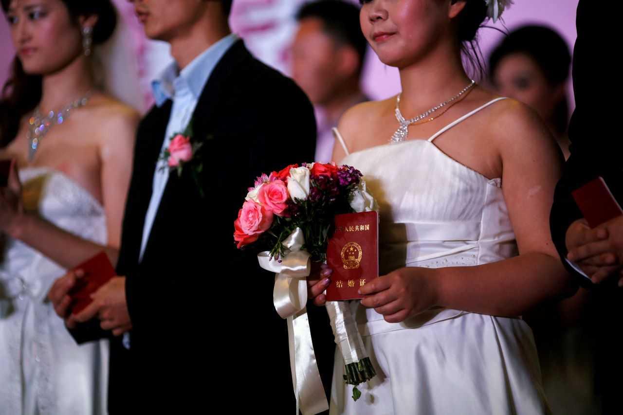 A woman holds her marriage certificate as couples participate in a staged mass wedding, organised as part of a matchmaking event to inspire singles to get married, in a suburban area of Shanghai May 18, 2013. Photo: Reuters