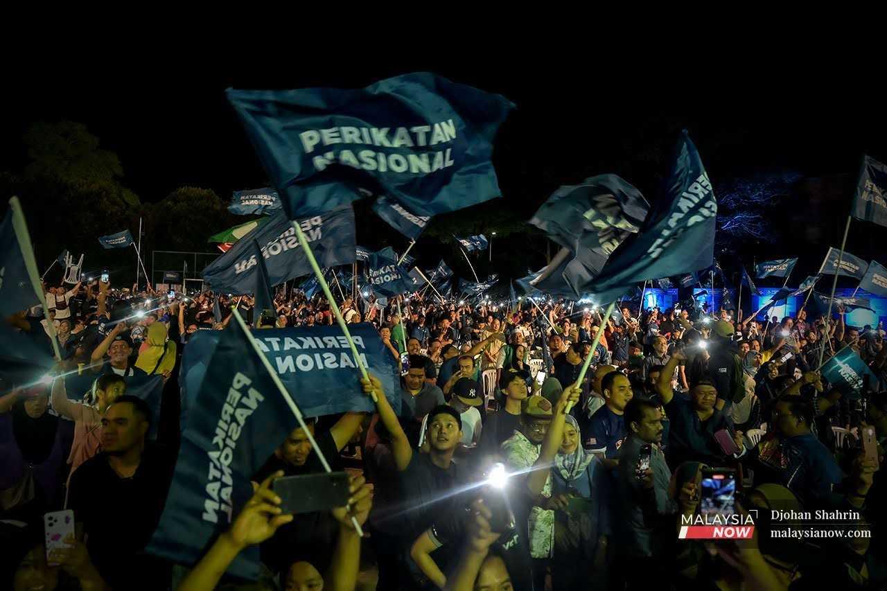 Penyokong mengibarkan bendera Perikatan Nasional semasa ceramah Grand Finale Selangor Bangkit Gemilang di Taman Melawati, Hulu Kelang, 11 Ogos.