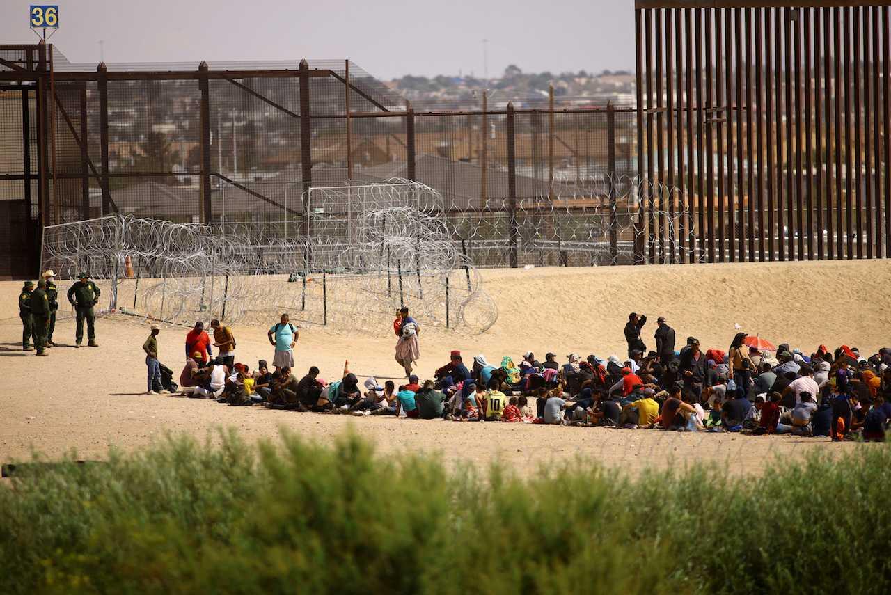 Migrants, mostly from Venezuela, gather near the border wall after crossing the Rio Bravo river with the intention of turning themselves in to US Border Patrol agents, as seen from Ciudad Juarez, Mexico, Sept 21. Photo: Reuters