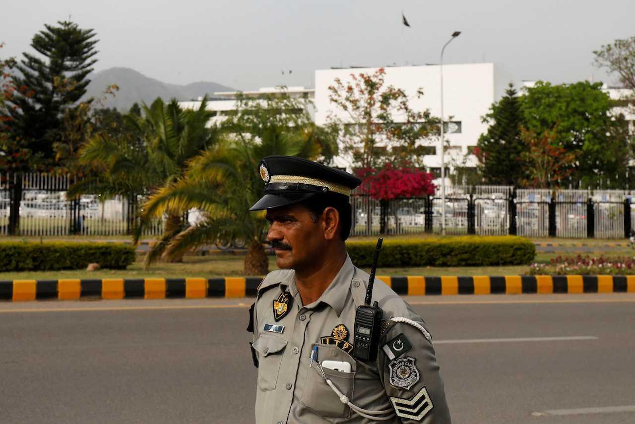 A police officer stands guard with the Parliament house building in the background, in Islamabad, Pakistan, April 11, 2022. Photo: Reuters