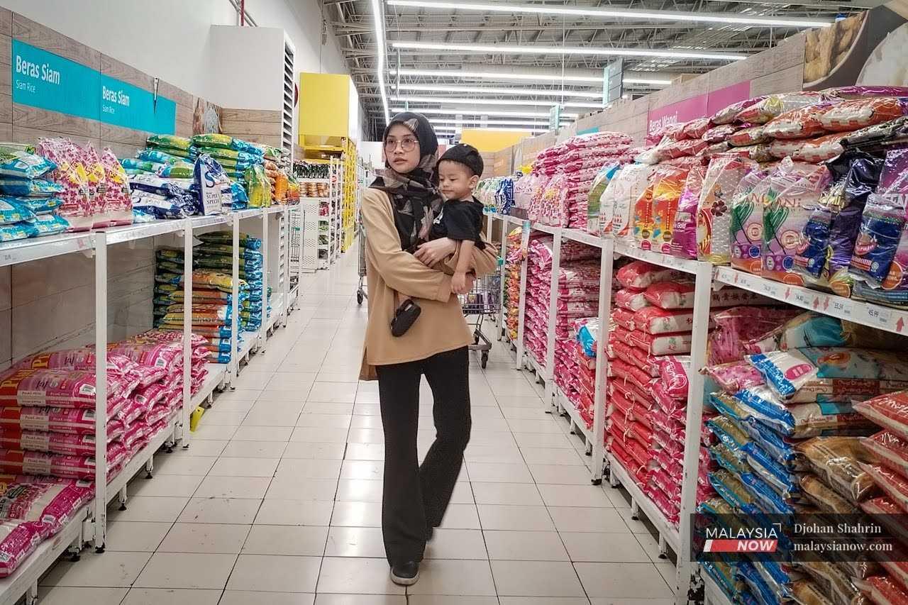 A woman carries her child down the imported rice aisle at a supermarket in Ampang.
