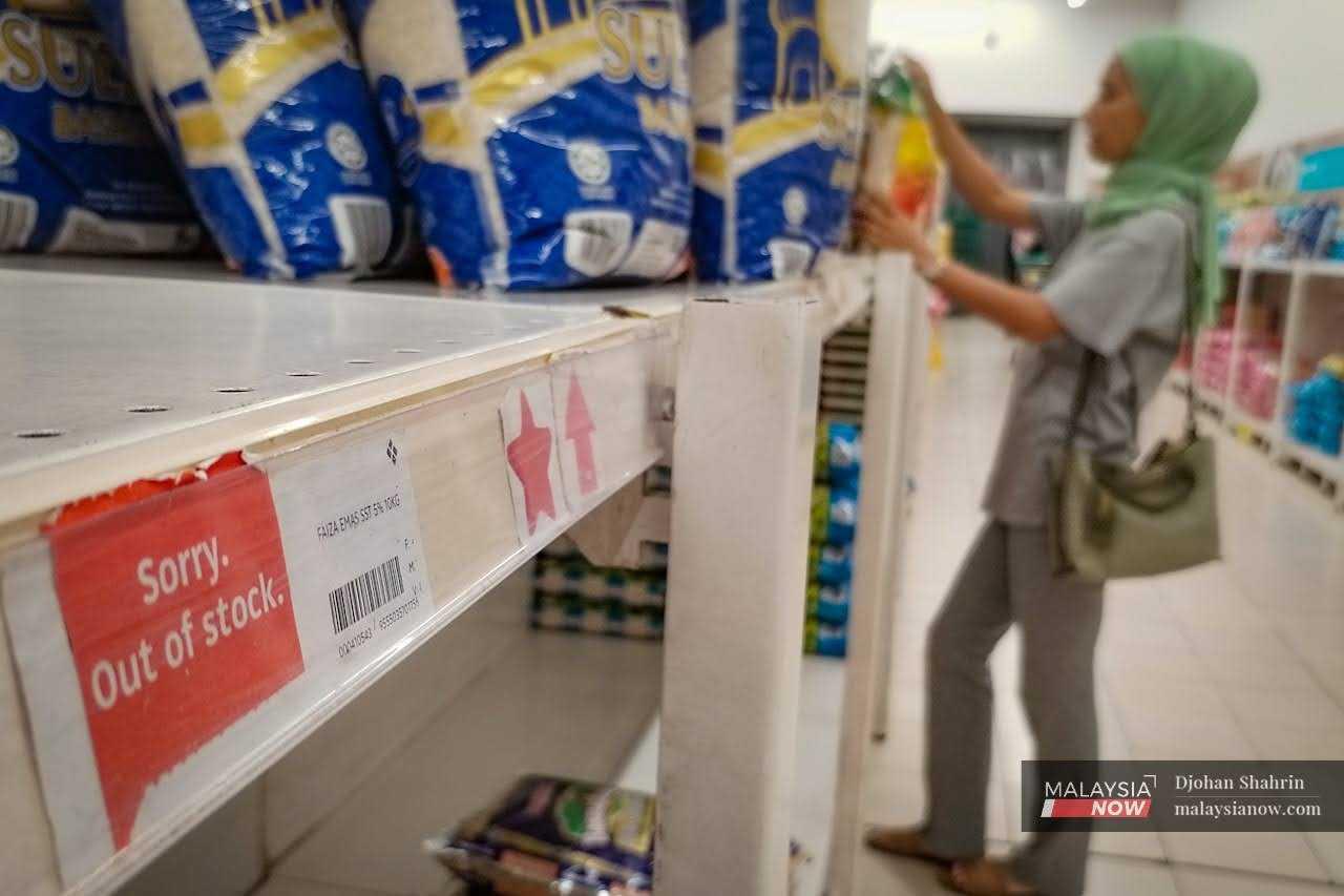Seorang wanita sedang memilih kampit beras import di bahagian rak jualan di sebuah pasar raya di Ampang.