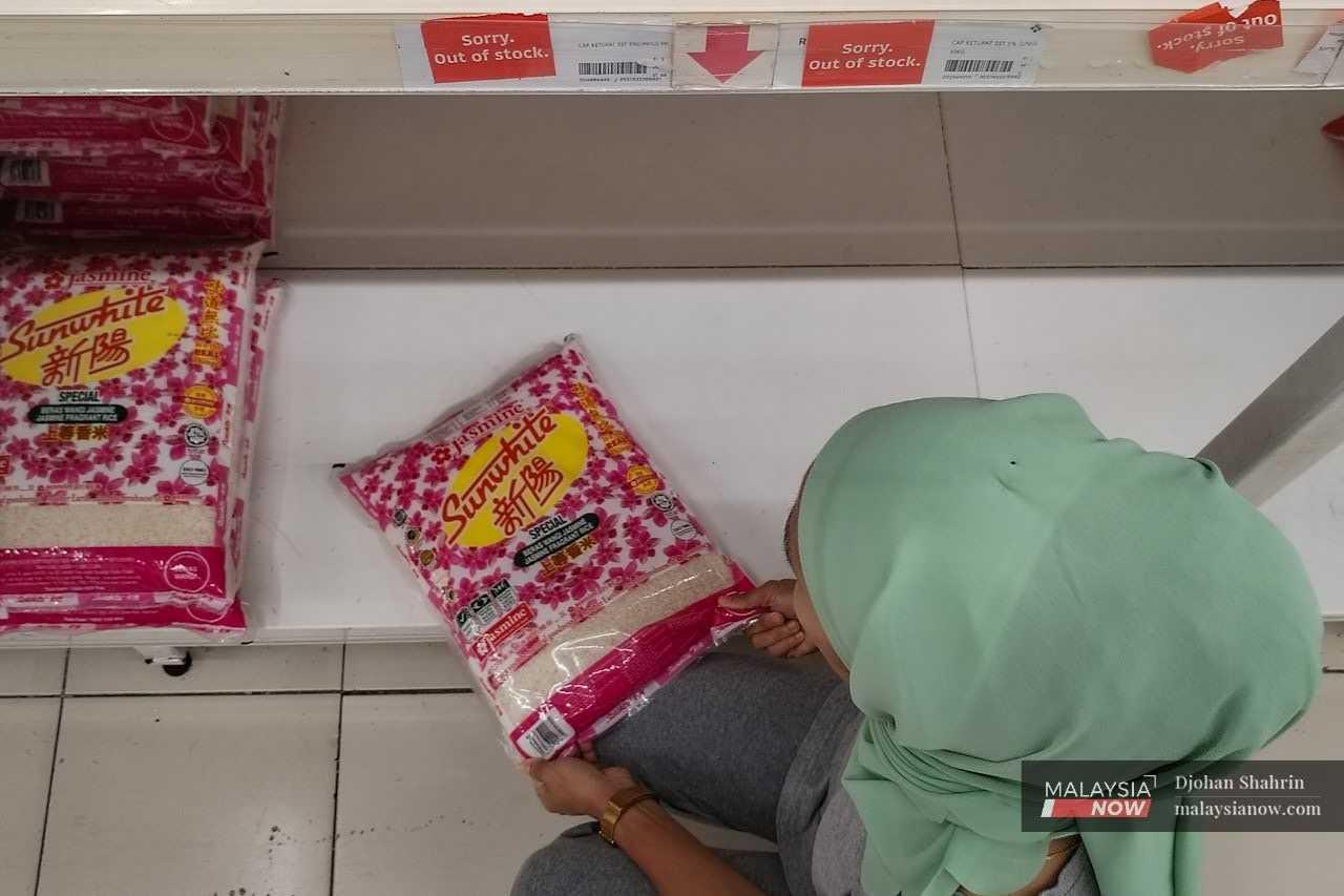 A woman examines a bag of rice at a supermarket in Ampang. 