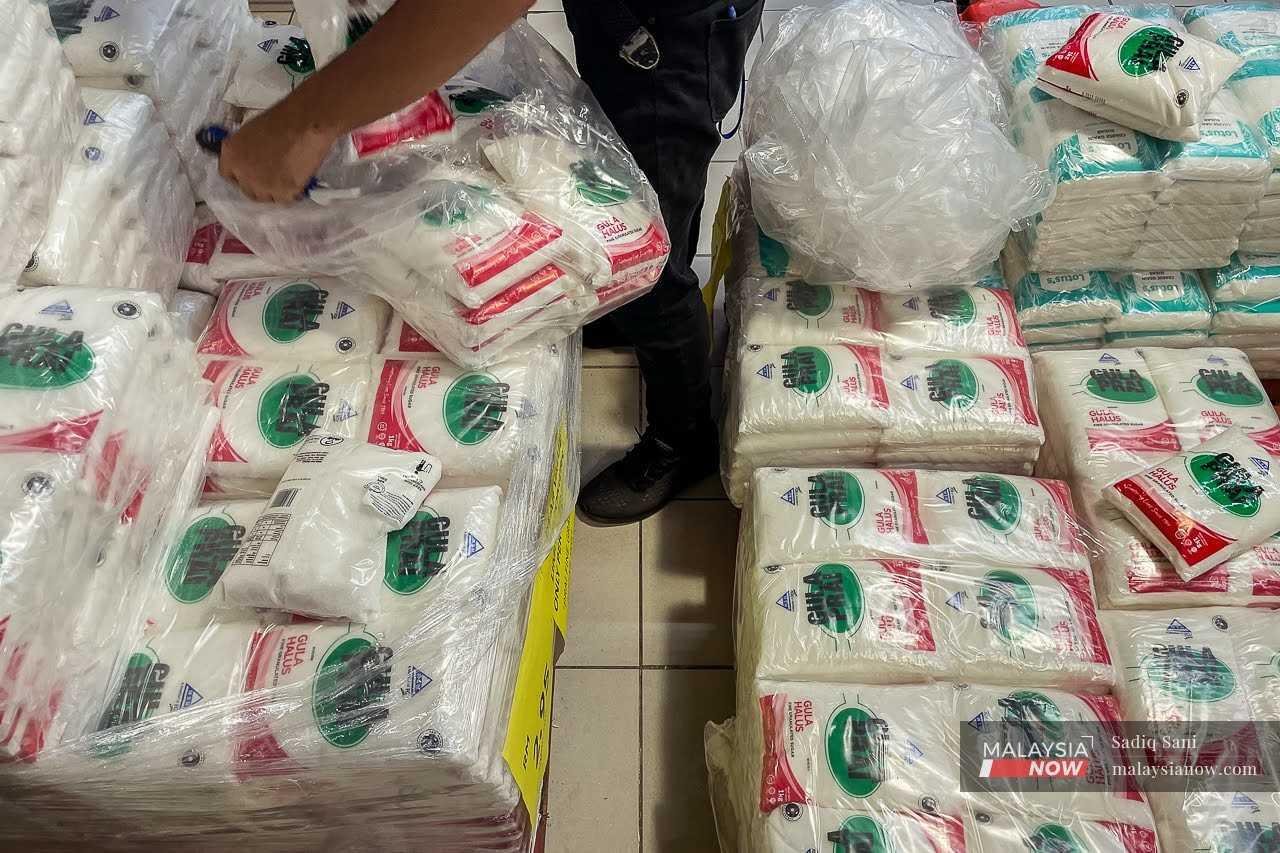 A worker sorts through bags of white sugar at a supermarket in Putrajaya.
