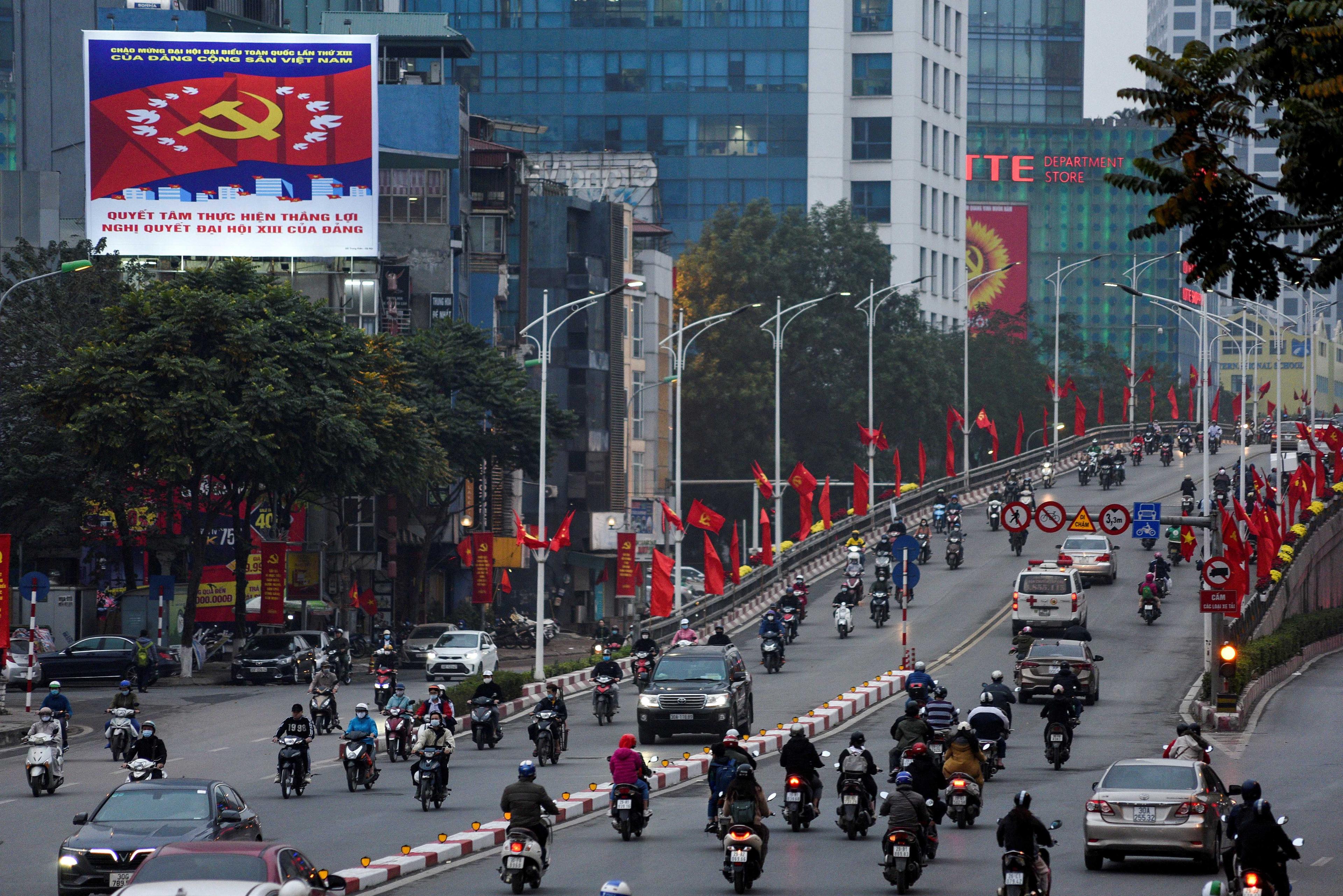 Kereta dan motosikal melintasi jalan yang dihiasi bendera negara itu di Hanoi, Vietnam, 25 Januari 2021. Gambar: Reuters