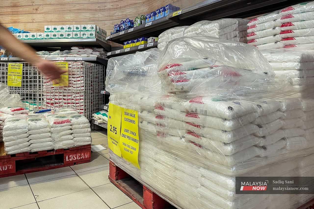 Beberapa paket gula putih disusun di atas rak di sebuah pasar raya di Putrajaya, dengan notis yang menunjukkan ‘terhad tiga paket setiap keluarga’.