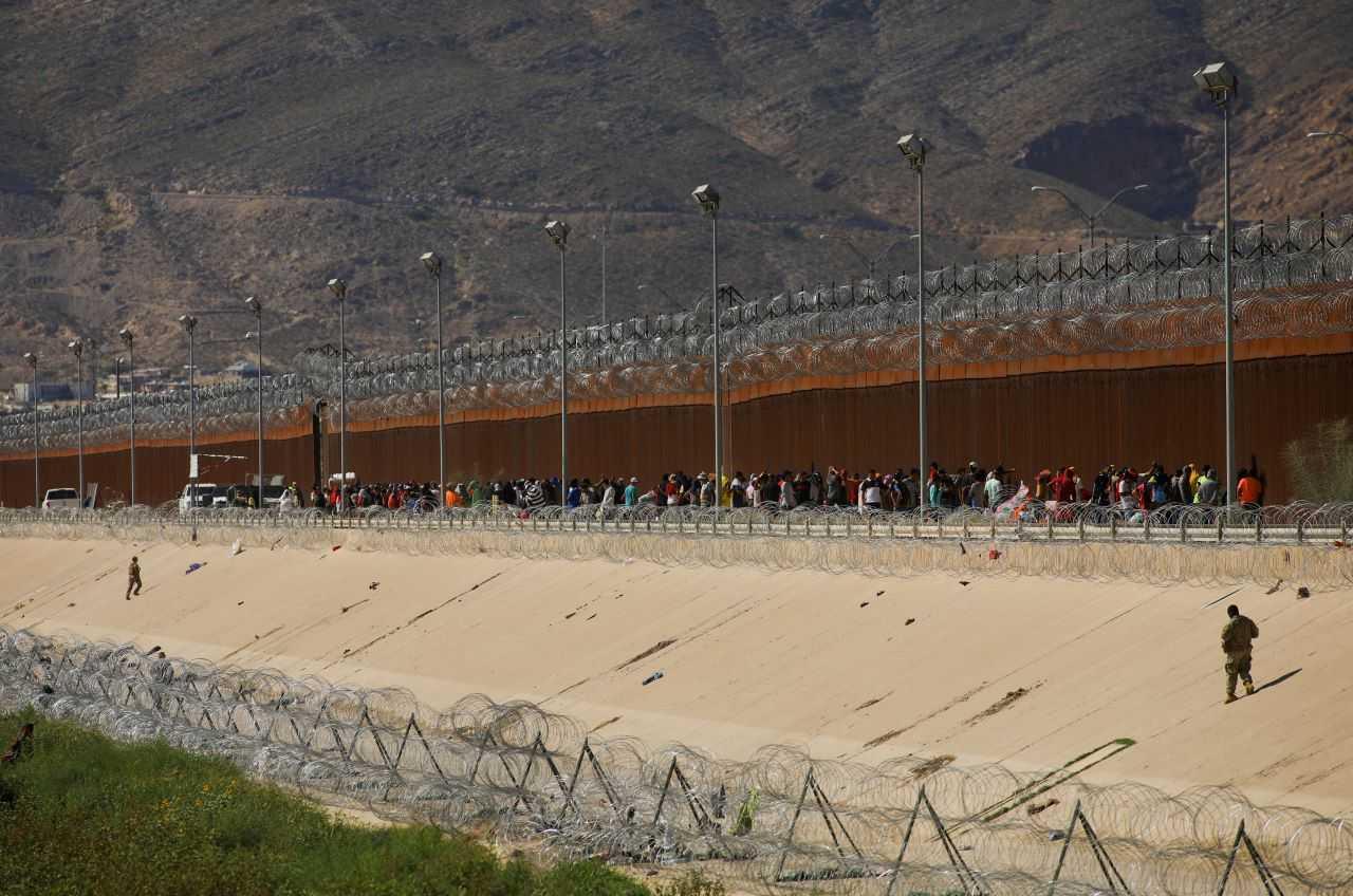 Migrants seeking asylum in the US gather near a border wall as members of the Texas National Guard stand guard on the border between the US and Mexico, as seen from Ciudad Juarez, Mexico Sept 18. Photo: Reuters