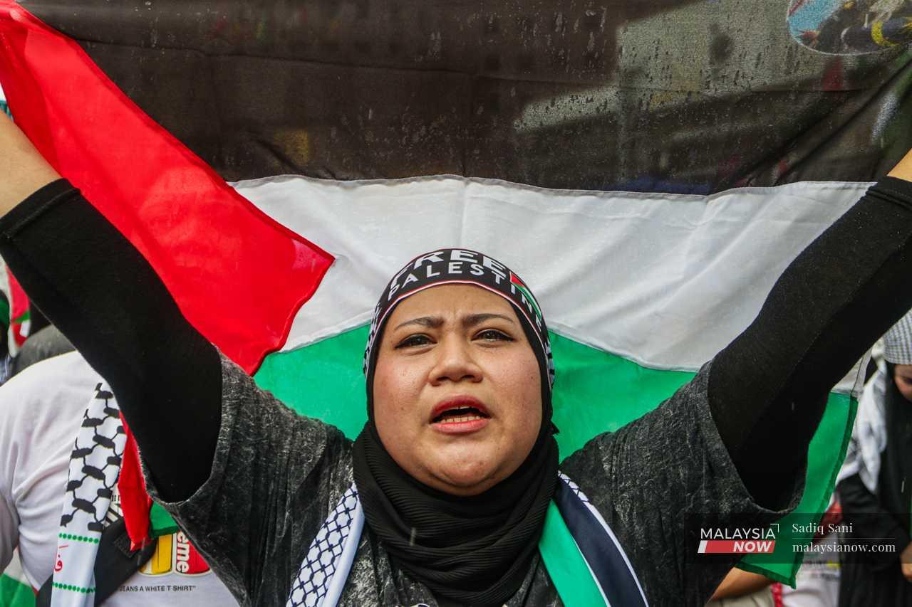 A woman holds up a Palestinian flag as she shouts slogans against Israel.