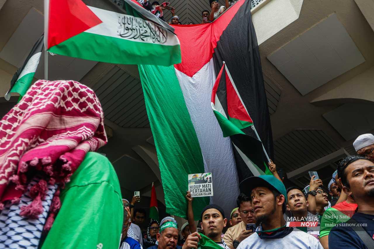 Protesters gather under a huge Palestinian flag at the Asy-Syakirin Mosque next to the Kuala Lumpur Twin Towers before marching to the US embassy in Jalan Tun Razak on October 28, 2023 to show their support and solidarity with the Palestinian people.