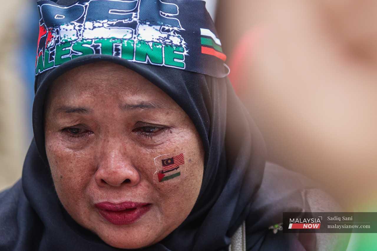 A woman cries as she joins in a prayer during the protest to denounce Israel's bombardment of Gaza, outside the US embassy in Kuala Lumpur.
