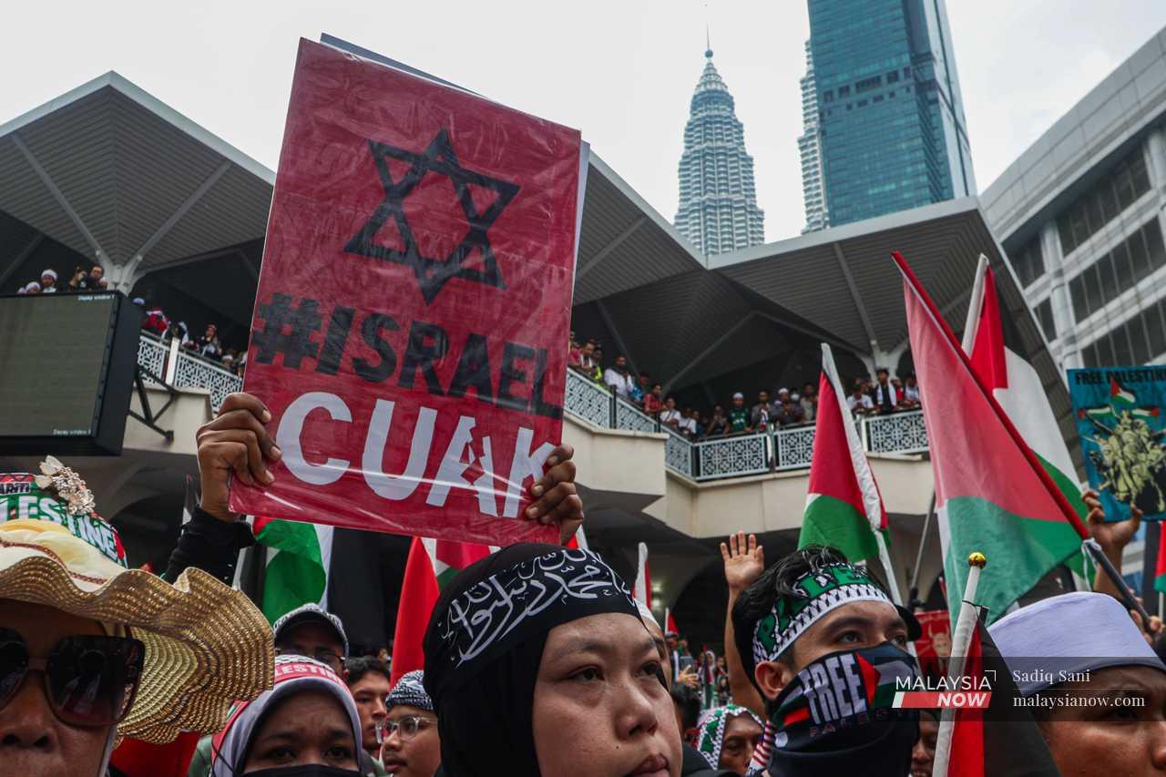 A protester holds a placard with a popular anti-Israel slogan among Malaysians, 'Israel Cuak' (Israel is scared) as they march towards the US embassy to express anger at Washington's support for the military campaign in Gaza.