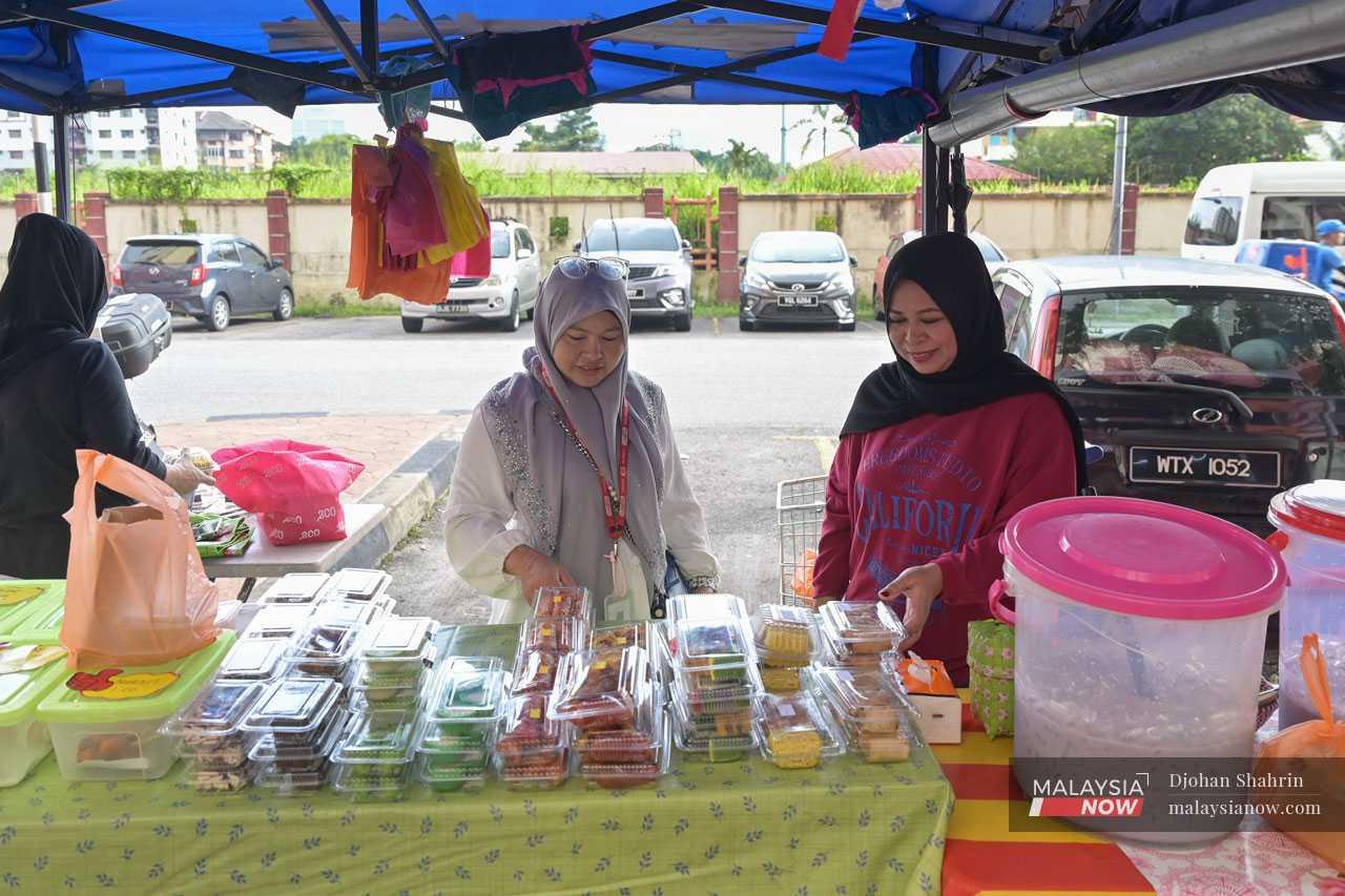 Normah Zakaria (right), 47, mans her small stall every day and worries about how to factor the rising costs into her prices.