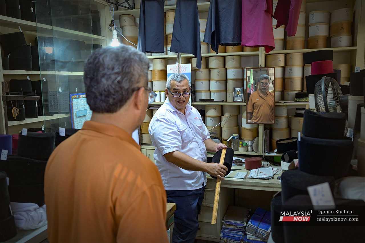 He entertains a customer who is looking for a songkok to wear during this year's festivities.