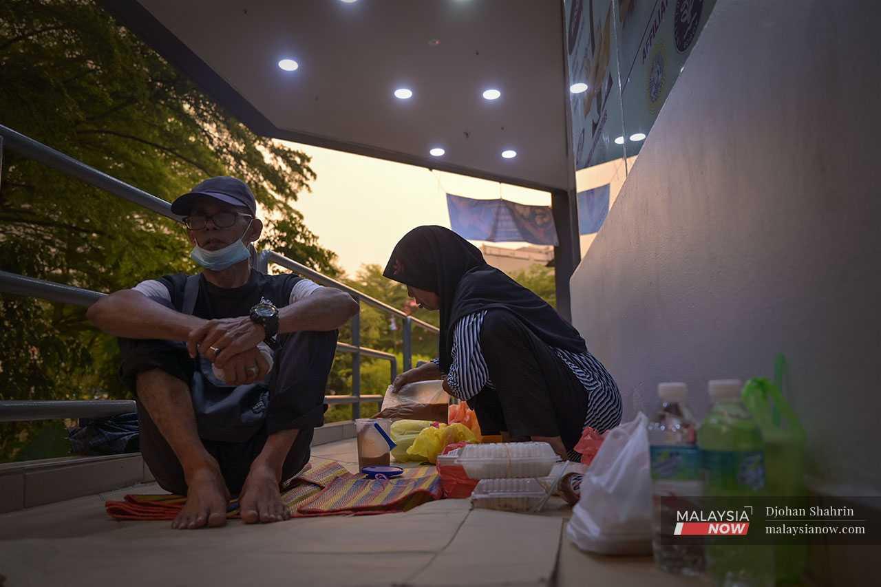 The elderly couple break their fast sitting on the floor of the five-foot way of a nearby building.
