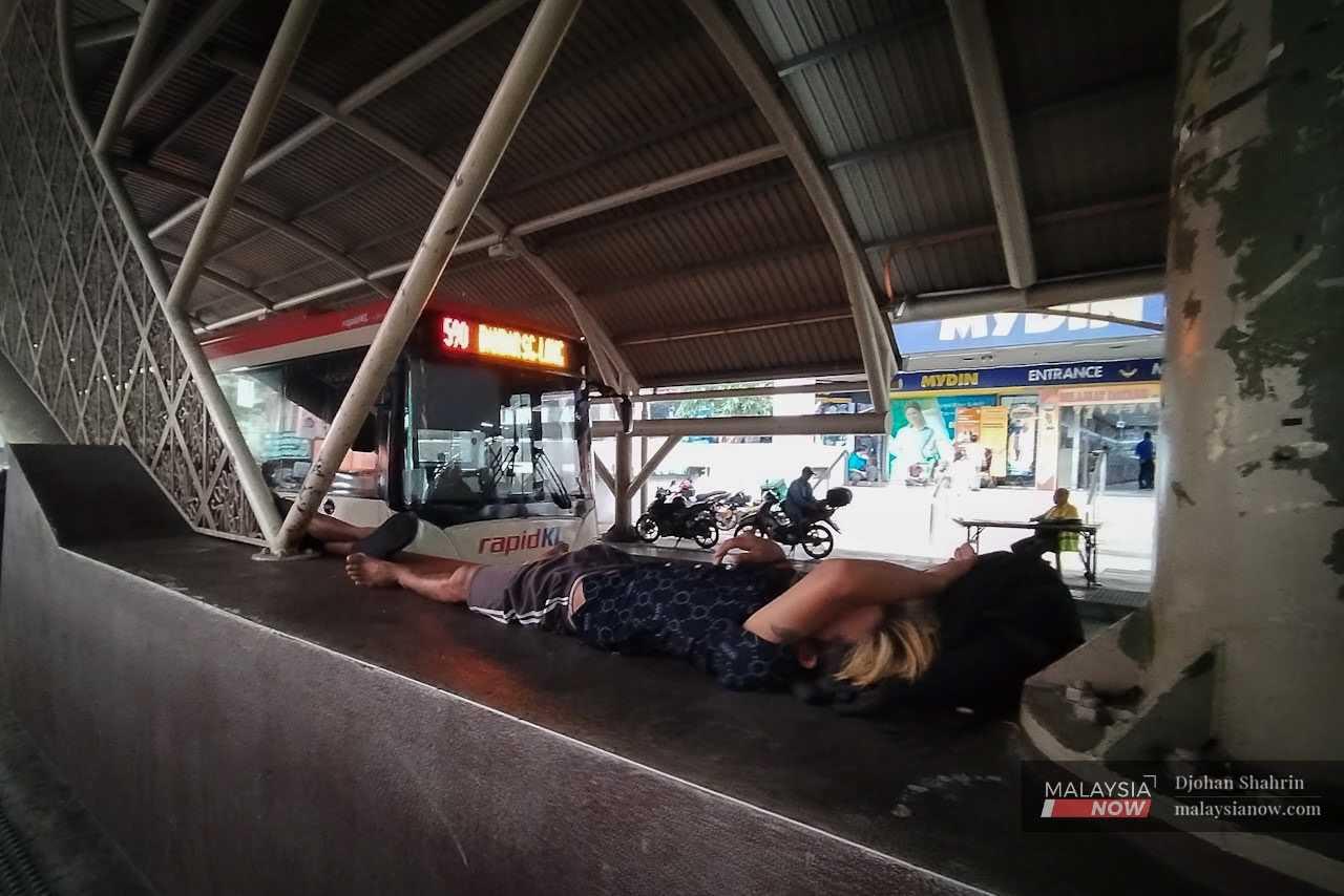 At the Lebuh Pudu bus station, another homeless man stretches out on the relative cool offered by the tiled surface.