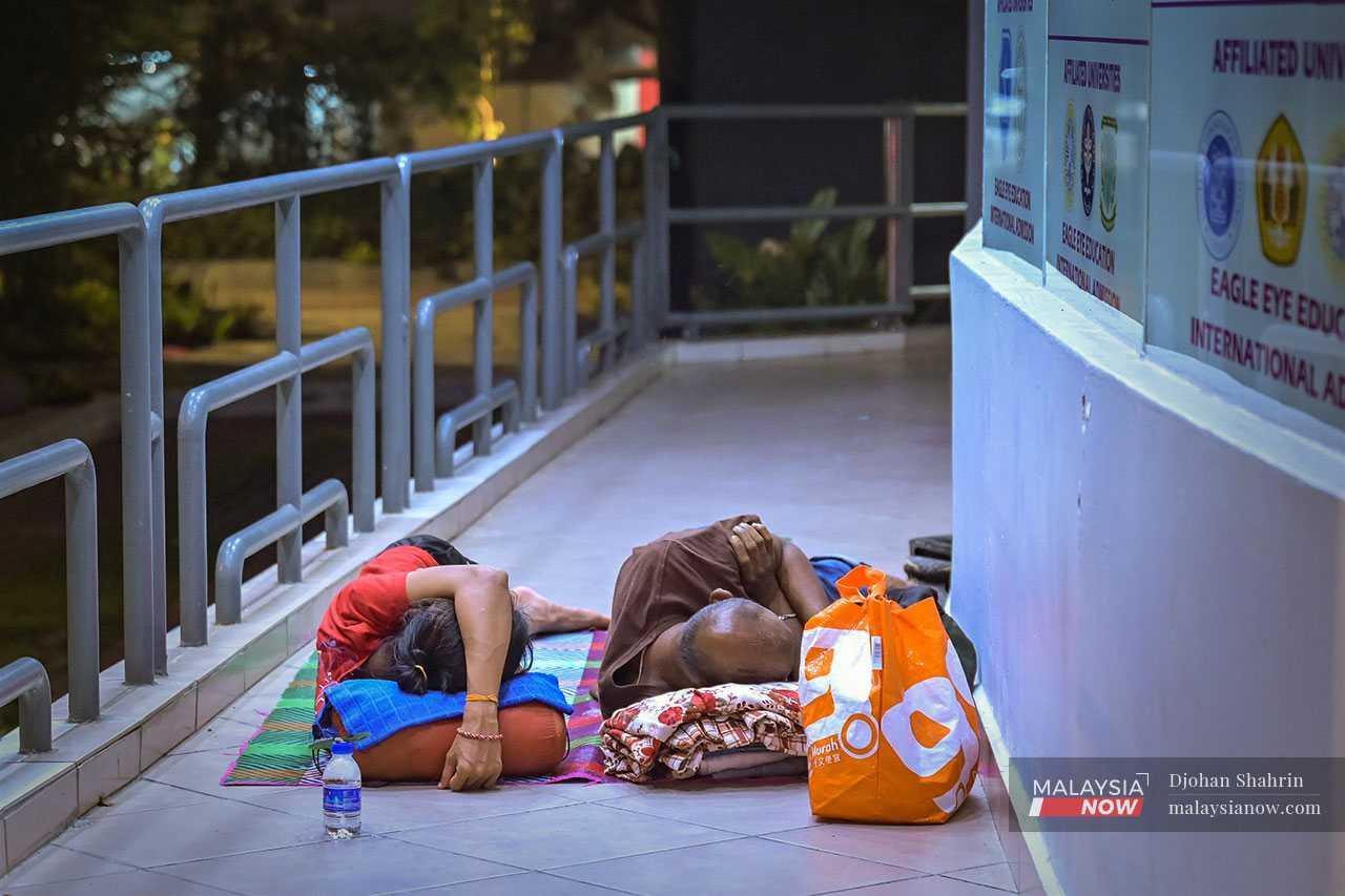 Pasangan gelandangan ini berbaring di atas tikar di kaki lima Bangunan Cahaya Suria di Jalan Pudu, manakala barangan mereka yang tak seberapa disusun bersebelahan.