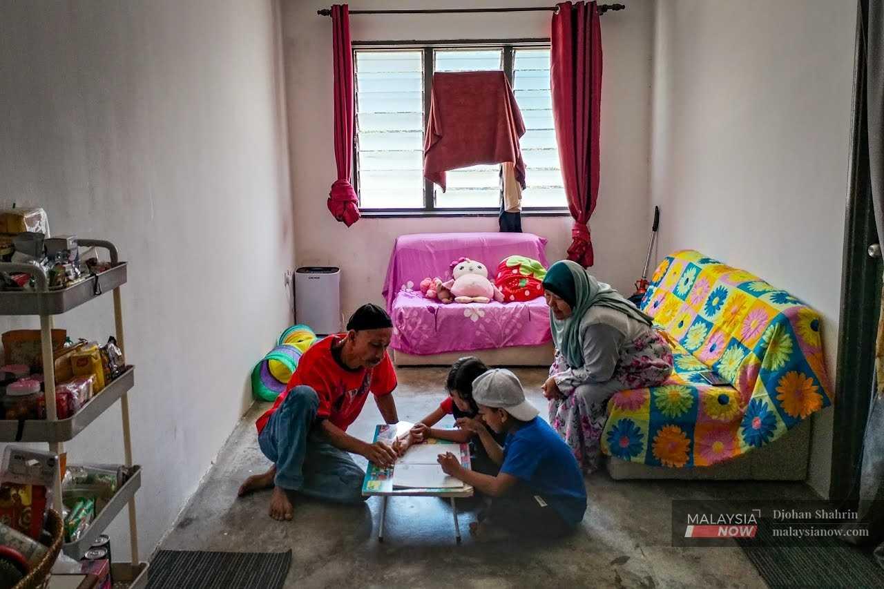 Zubir Ramli and his wife Noraini Hasan teaching Muhammad Ziqri and Fatihah Qaisara at their home. The children were taken into their care after their mother vanished to Indonesia, and are among thousands denied formal education du eto their stateless status.