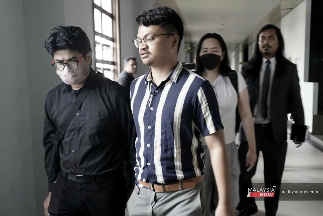 Peserta perhimpunan pro-Palestin Isa Hazmi Zulkifli (berbaju hitam) bersama Kamal Aarif Kamaruddin ketika di mahkamah, ditemani peguam mereka Zaid Malek, 31 Disember 2025.