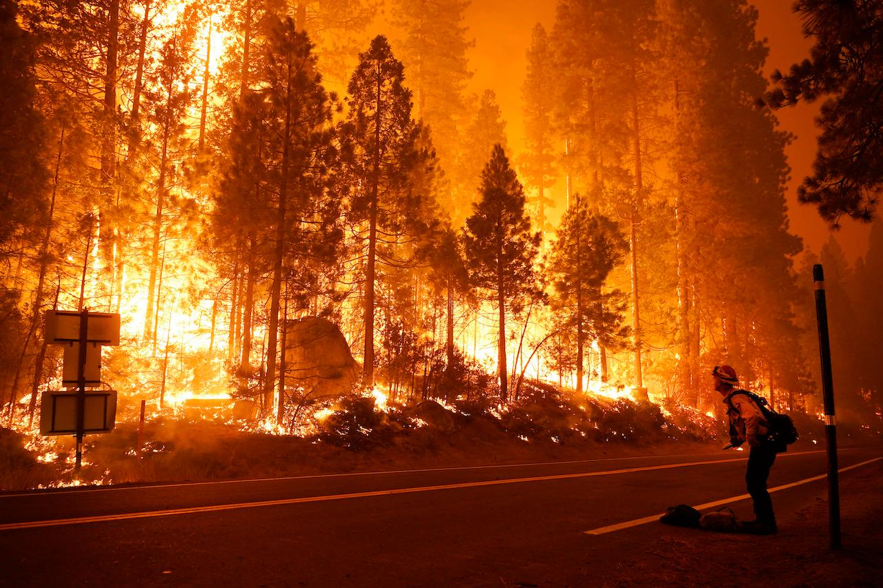 A firefighter stands near a fire raging along a highway in California on Sept 6, 2020. Photo: AP