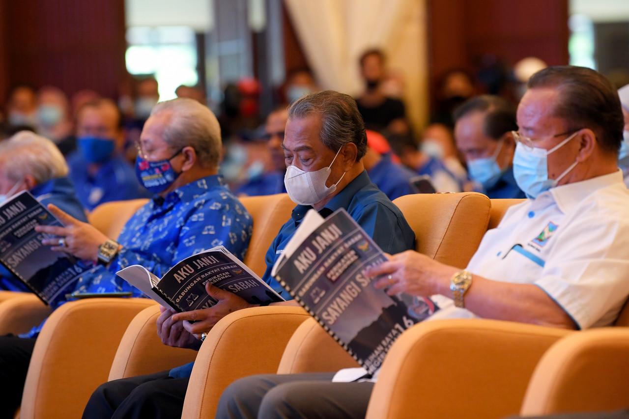Perdana Menteri Muhyiddin Yassin (tengah) mengimbas buku Aku Janji pada pelancaran buku Aku Janji Gabungan Rakyat Sabah untuk Perikatan Nasional dan Barisan Nasional Pilihan Raya Negeri Sabah ke-16 di sebuah hotel di Kota Kinabalu hari ini. Gambar: Bernama