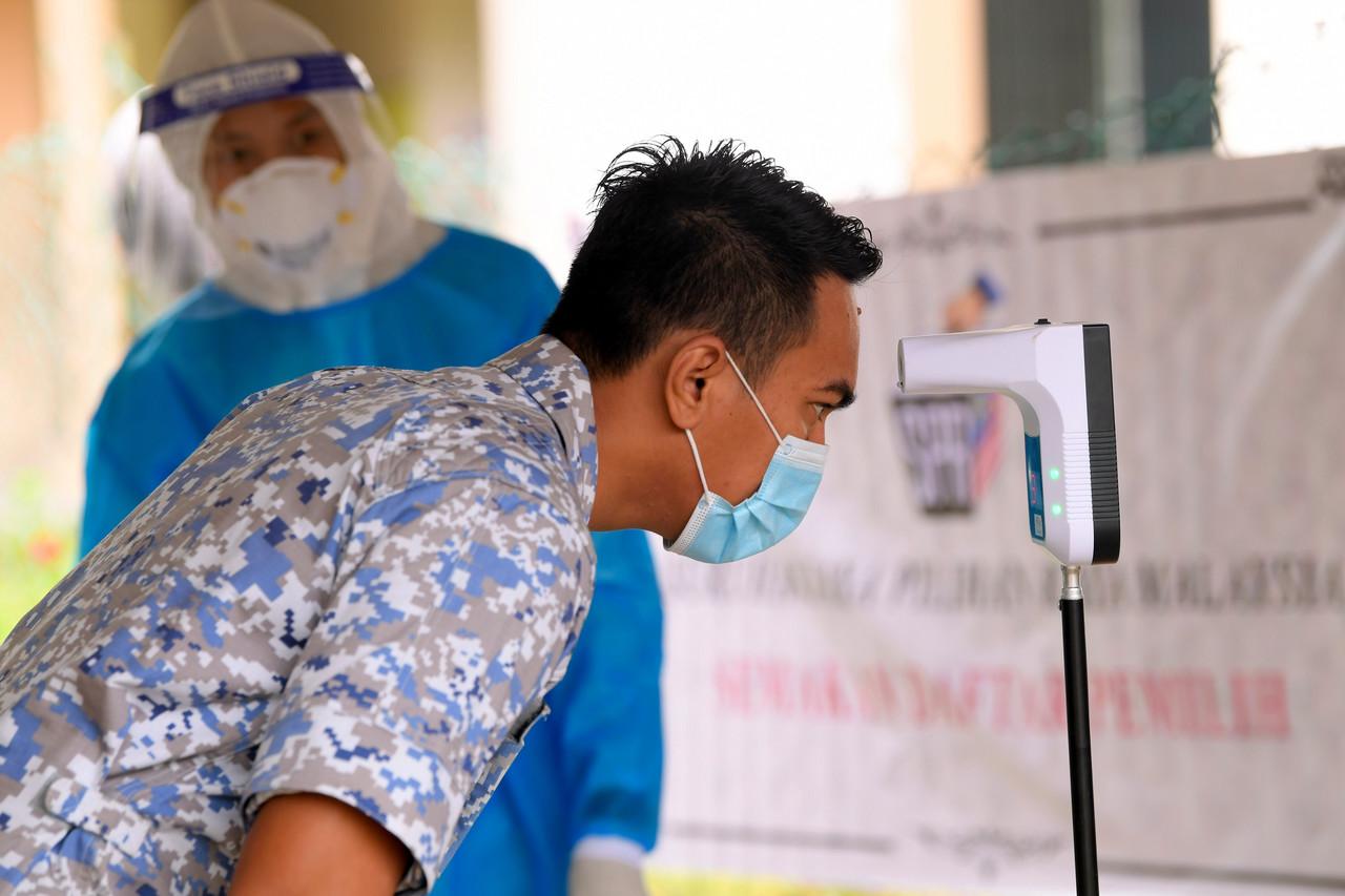 An army officer in Sabah checks his temperature before casting his ballot in early voting today. Photo: Bernama