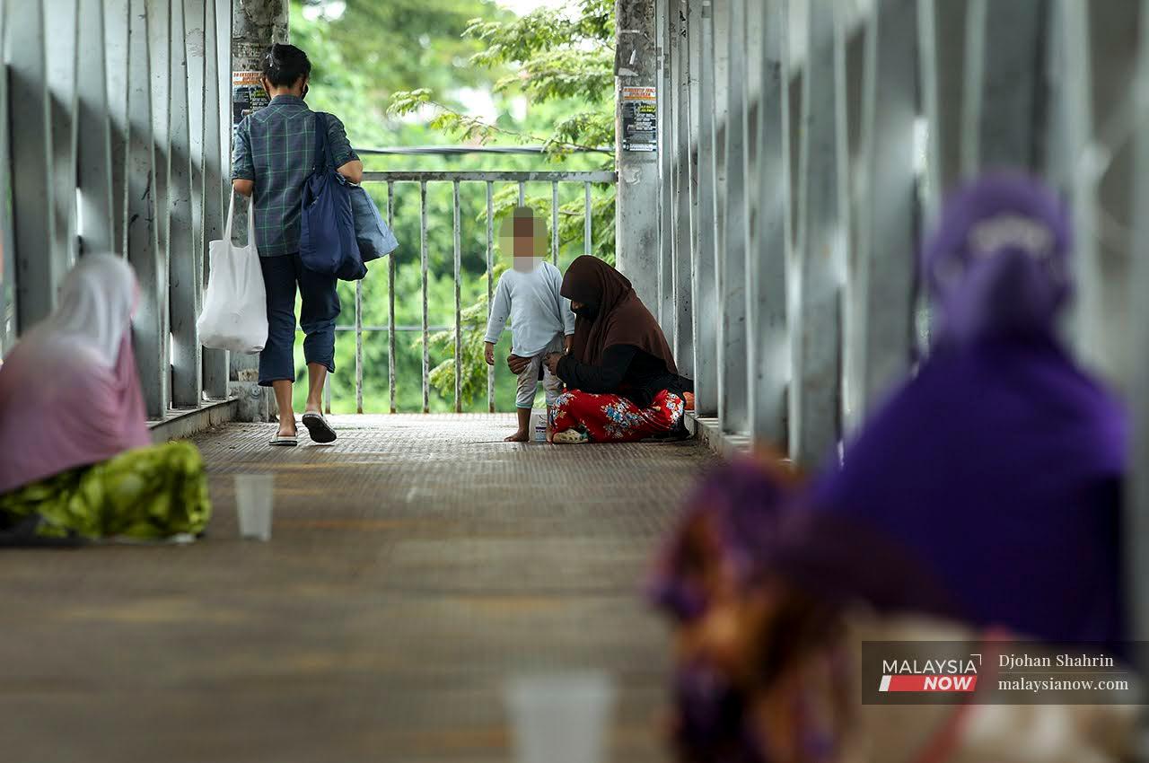 A Burmese woman begs with her child in Ampang Point, Kuala Lumpur.