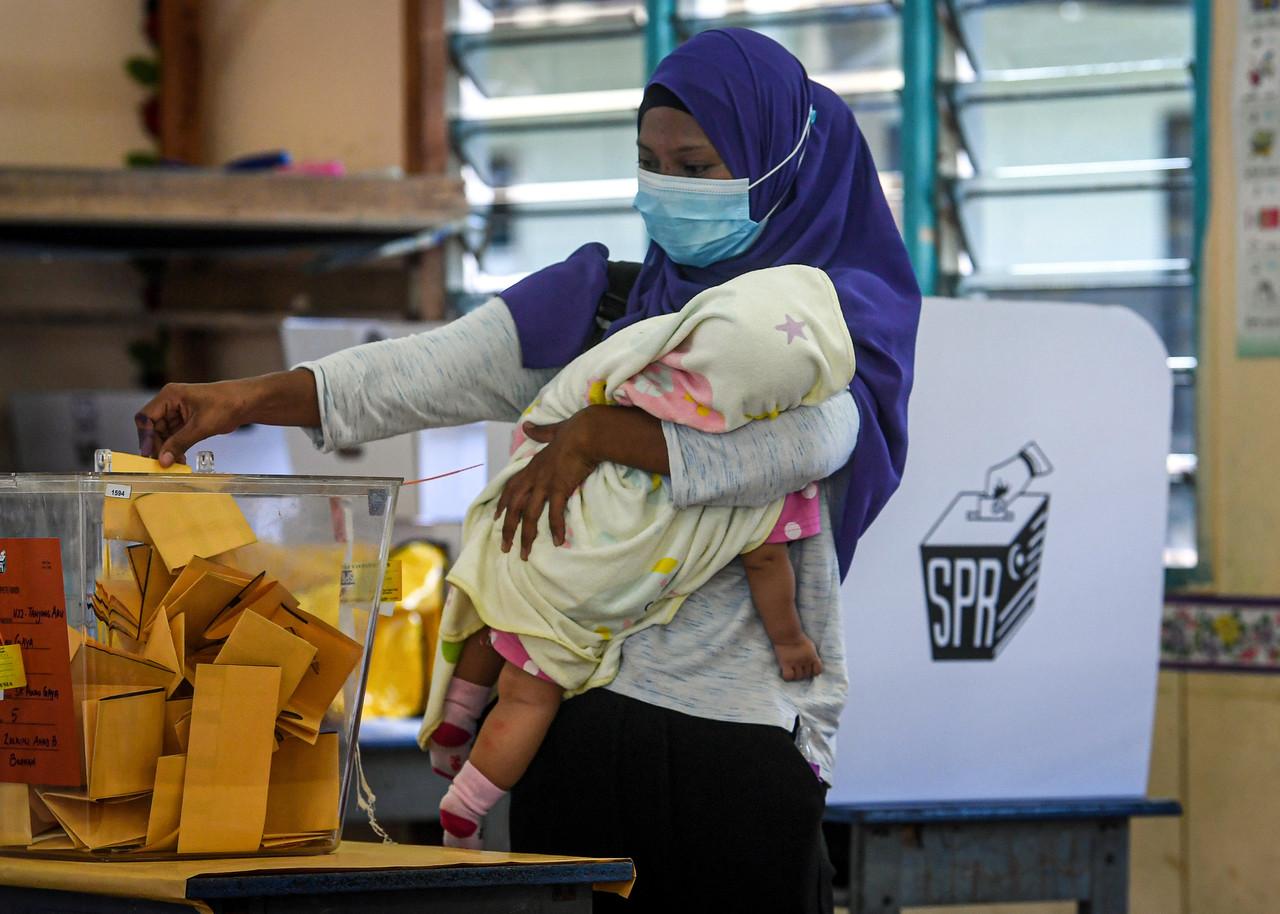 Seorang pengundi terpaksa membawa anak semasa mengundi pada hari pengundian Pilihan Raya Negeri Sabah ke-16 di Sekolah Kebangsaan Pulau Gaya hari ini. Gambar: Bernama