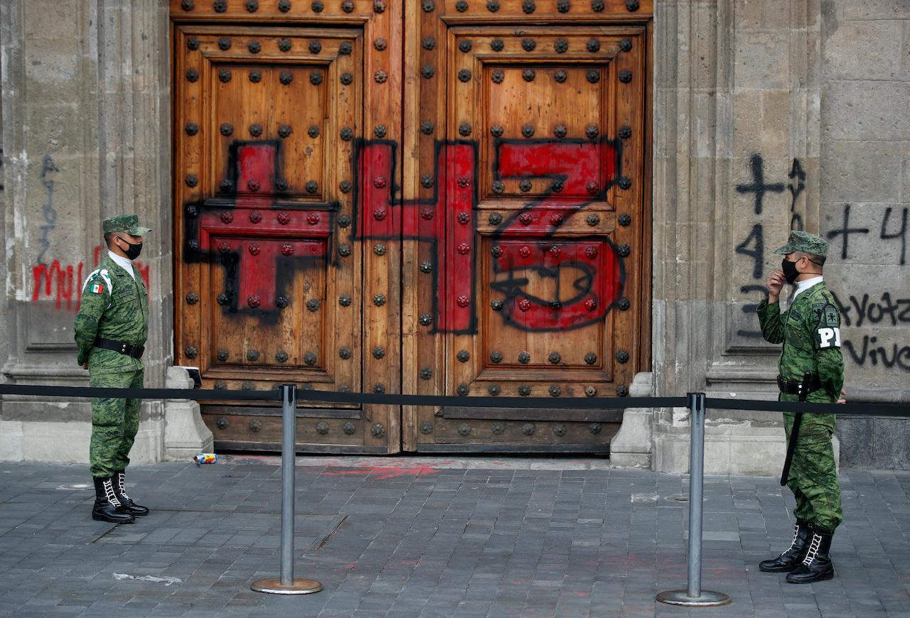 Guards return to their post in front of the National Palace doors after protesters painted graffiti across the front of the palace, following a march by students and family members of 43 missing teachers' college students on the sixth anniversary of the students' forced disappearance, in Mexico City, Sept 26. Photo: AP