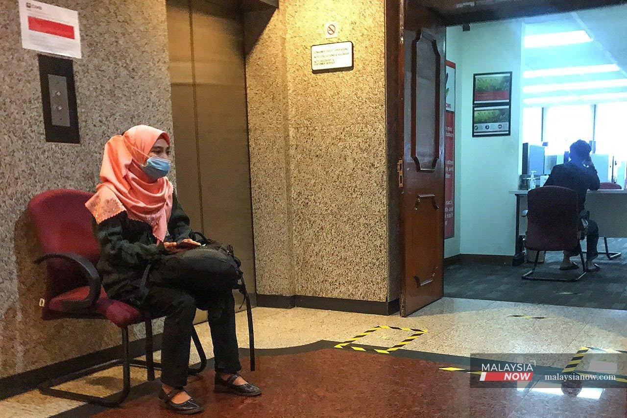 Seorang wanita menunggu gilirannya untuk bertemu dengan pegawai bank.