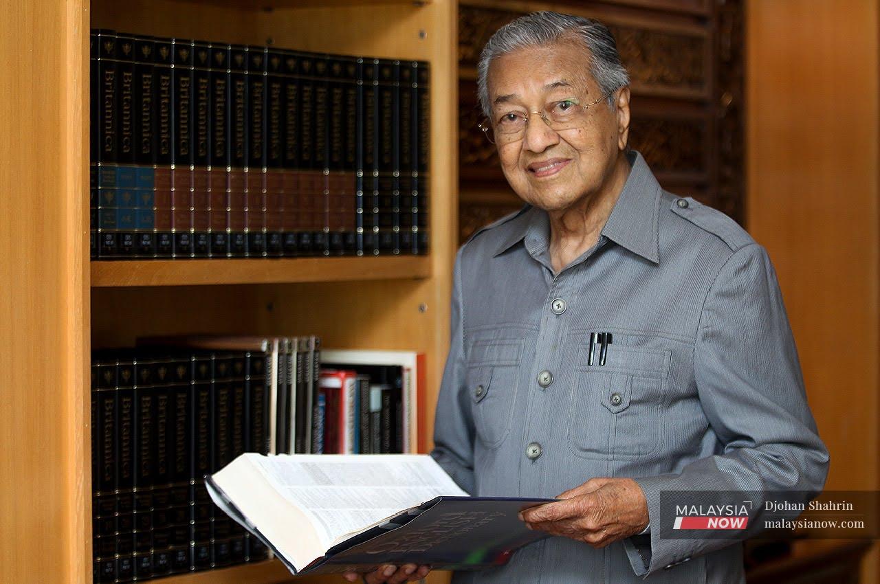 Former prime minister Dr Mahathir Mohamad holds a book in his office at Yayasan Kepimpinan Perdana, Putrajaya, during an interview with MalaysiaNow.