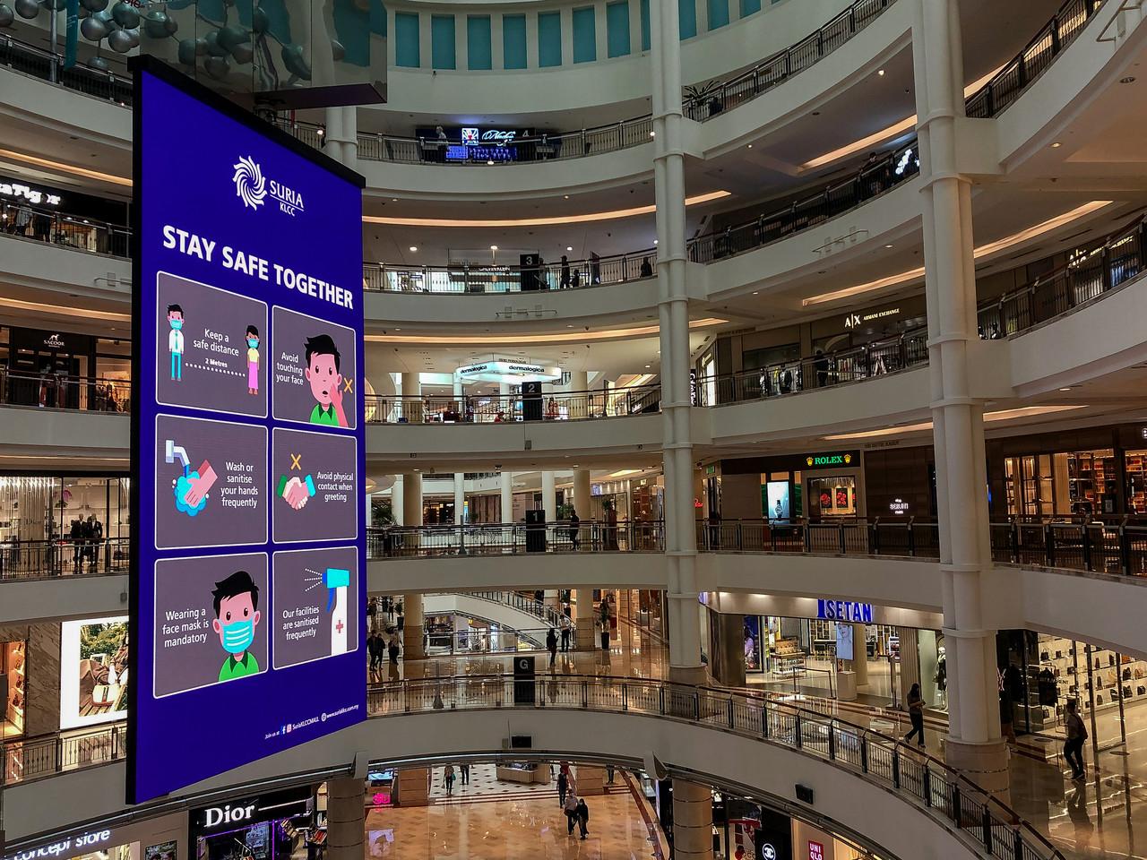 A message reminding customers to comply with Covid-19 SOPs looms over shoppers at the Suria KLCC mall in Kuala Lumpur. Photo: Bernama