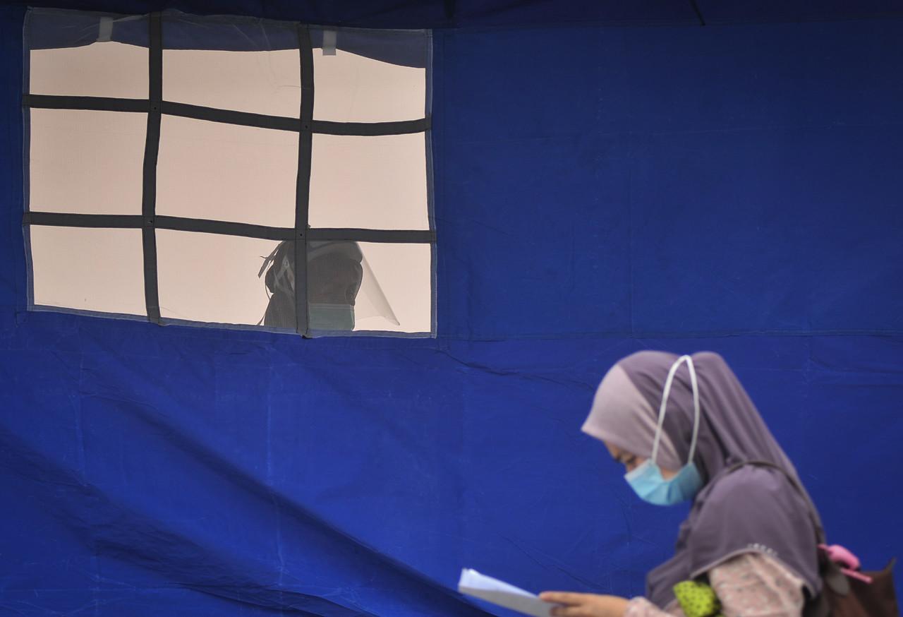 A woman walks past a tent where health workers conduct screening for Covid-19 in Labuan today. Photo: Bernama