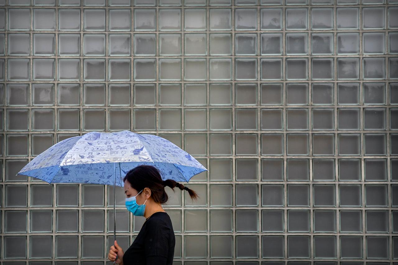 A woman wearing a face mask to protect against the coronavirus walks past a shopping mall on a rainy day in Beijing, Sept 23. Photo: AP