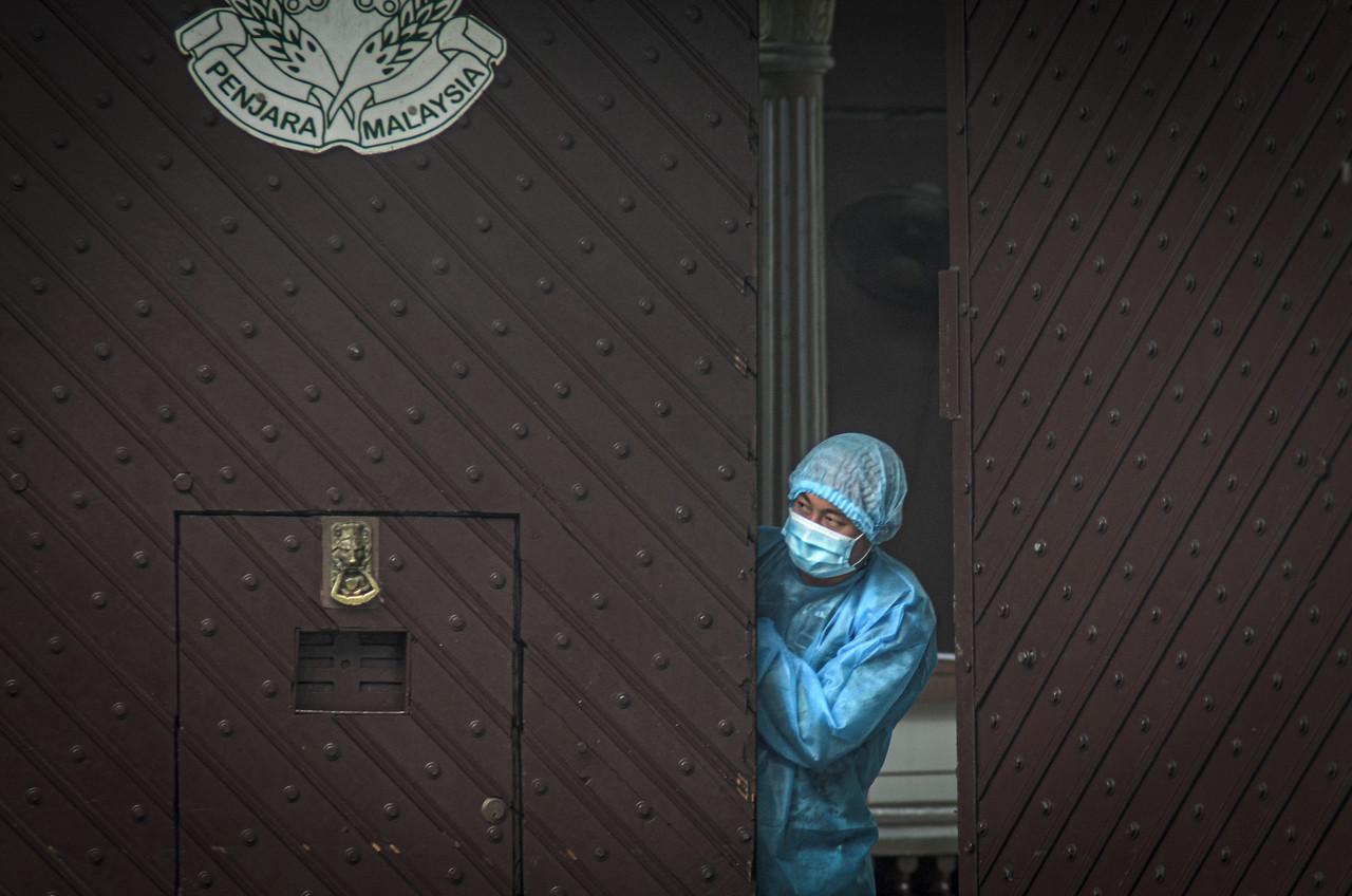 A health worker wearing protective gear looks out from the Penang Remand Prison in George Town today. Photo: Bernama