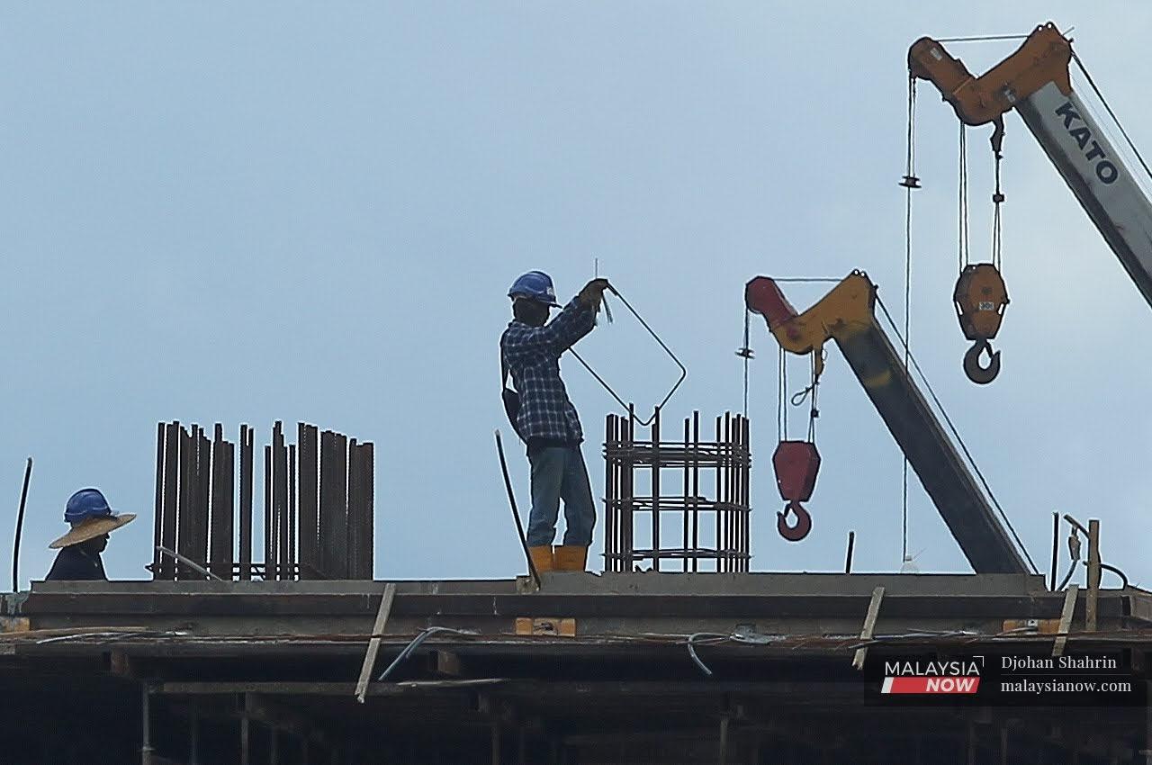 Dua orang buruh binaan melakukan kerja-kerja pembinaan di Jalan Sungai Besi, Kuala Lumpur.