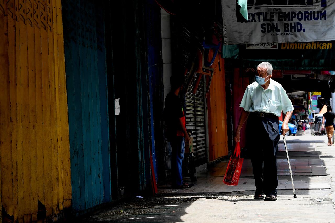 A man walks past a row of shops in Sandakan, all closed in the wake of the conditional movement control order imposed earlier this month following a spike in Covid-19 cases. Photo: Bernama