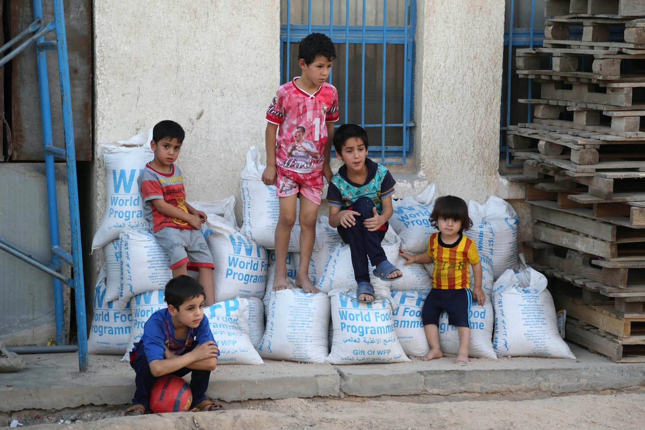 Children sit on bags of rice from the World Food Programme in the eastern Baghdad district of Jamila in Iraq, on June 19, 2015. Photo: AP