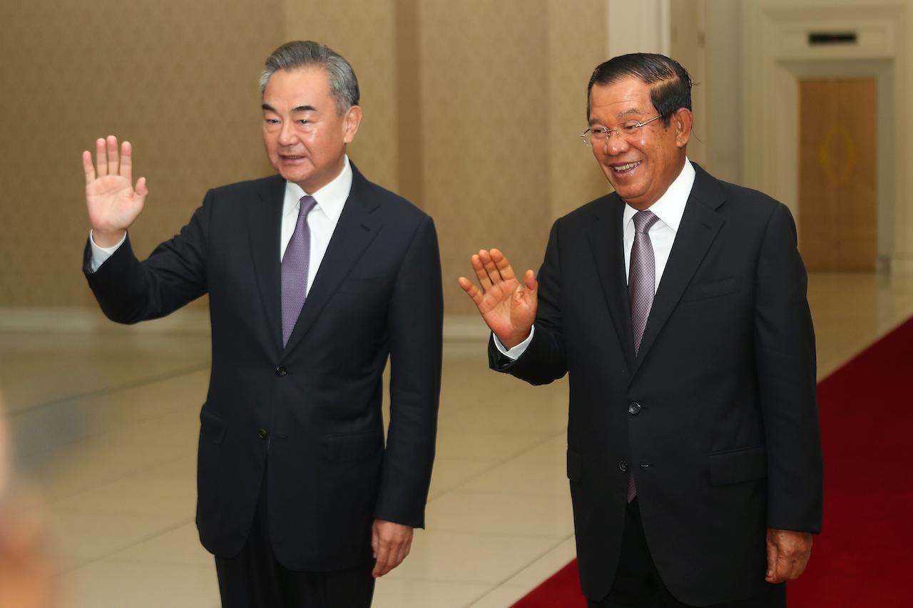 Chinese Foreign Minister Wang Yi (left) waves with Cambodian Prime Minister Hun Sen ahead of a meeting at Peace Palace in Phnom Penh, Cambodia on Oct 12. Photo: AP