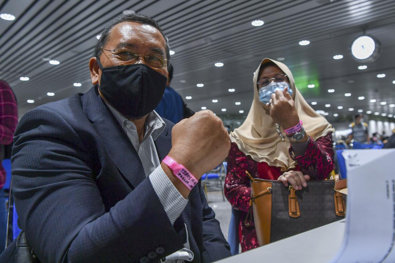 Pengerusi Suruhanjaya Pilihan Raya (SPR) Abdul Ghani Salleh dan isteri Siti Rohaya Sarman menunjukkan gelang tangan berwarna merah jambu selepas selesai melalui proses ujian saringan Covid-19 sejurus tiba di Lapangan Terbang Antarabangsa Kuala Lumpur (KLIA) pada 28 September lalu.