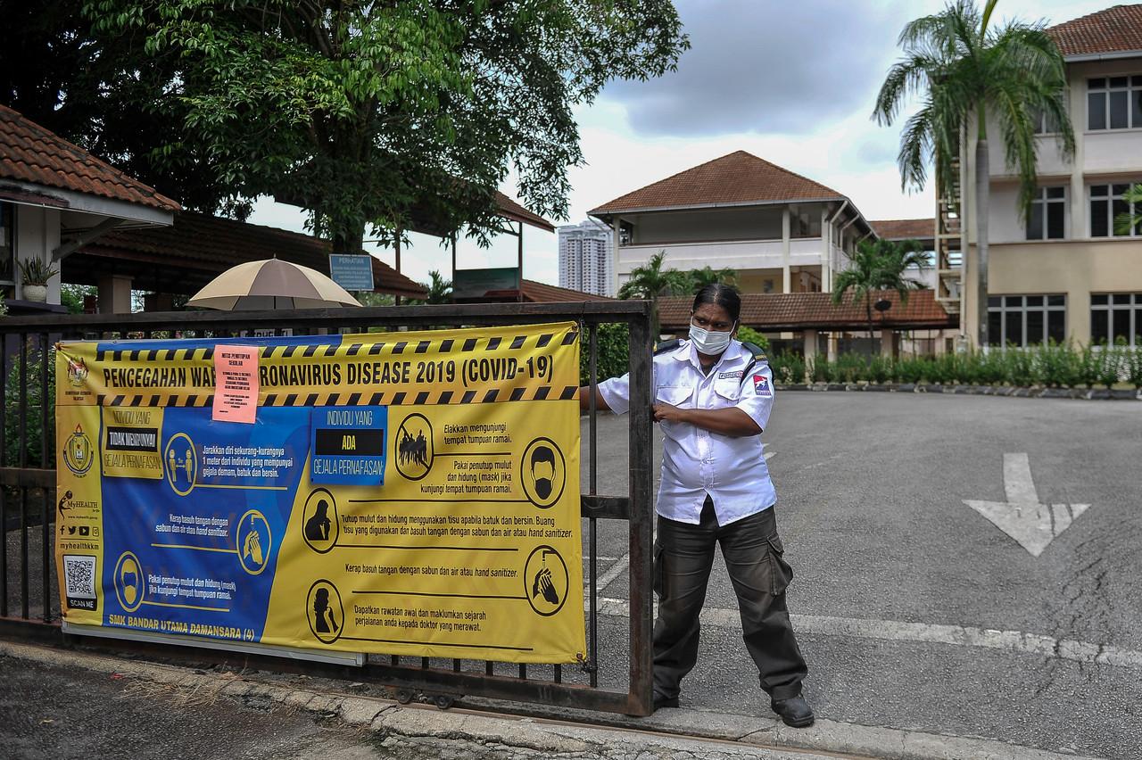 A security guard shuts the gate of a secondary school in Petaling Jaya after the government's announcement that hundreds of schools in the district would be closed due to the Covid-19 situation. Photo: Bernama