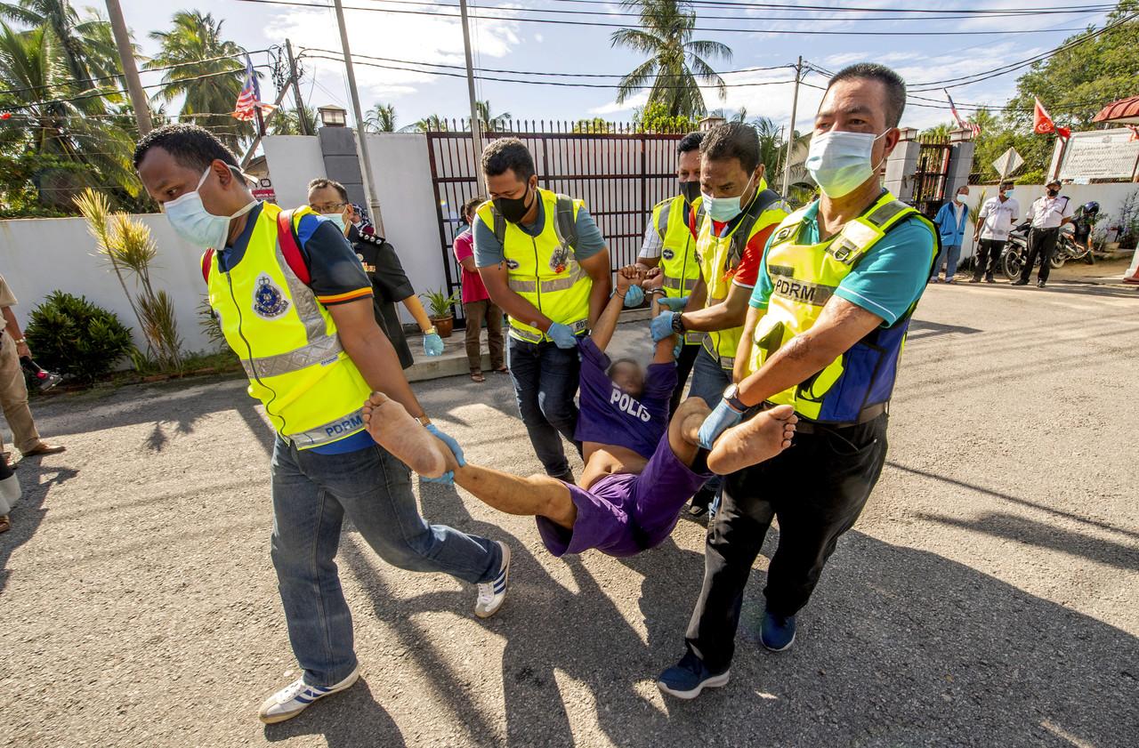 Police officers carry a man into the Magistrate's Court in Bachok after he refused to cooperate and enter of his own accord. Photo: Bernama