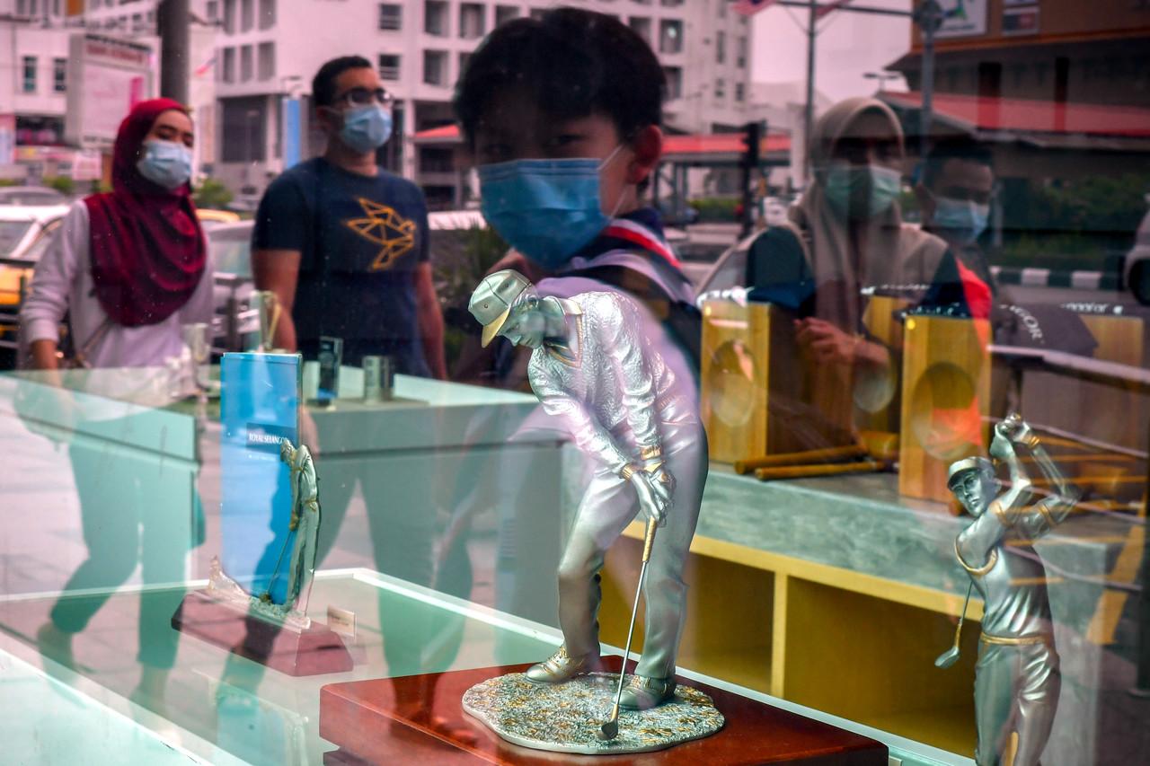 Passersby wearing face masks are reflected in the window of a shop in Melaka as measures to contain the spread of Covid-19 continue. Photo: Bernama