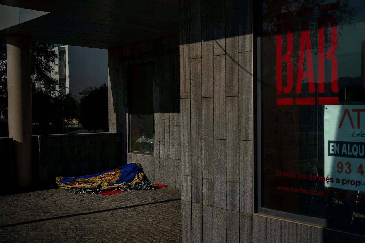 A homeless person sleeps at the entrance of a closed restaurant in Barcelona, Spain on Oct 18. Photo: AP