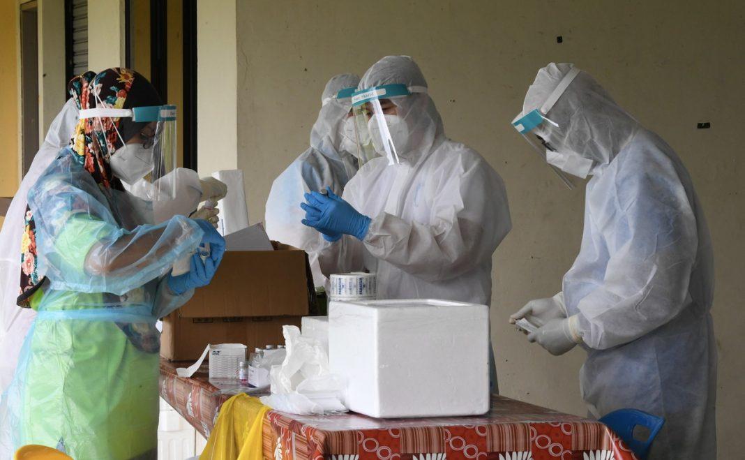 Kakitangan jabatan kesihatan Kota Kinabalu memakai sut PPE bagi mengumpul sampel Covid-19 sebelum dihantar ke makmal untuk diuji. Gambar: Bernama