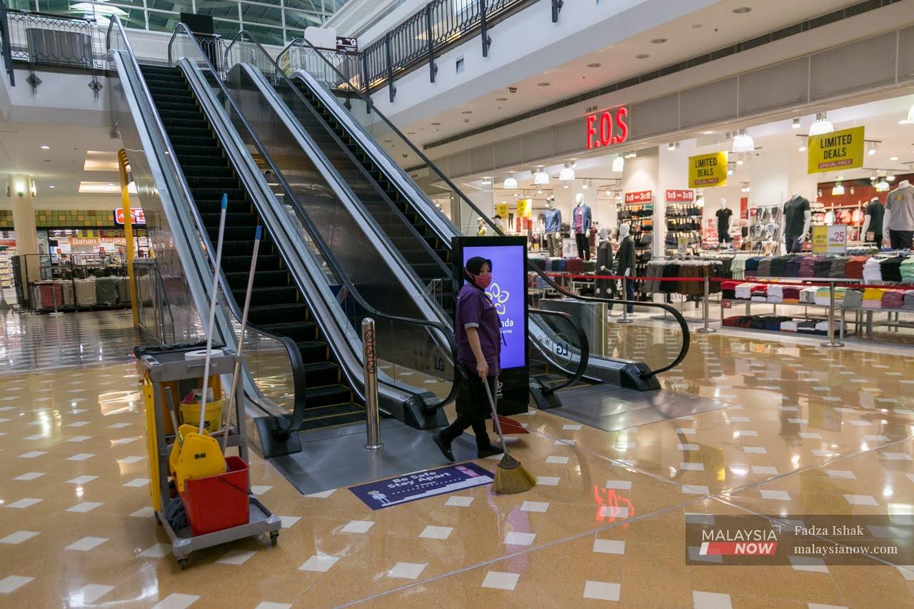 A cleaner walks past an escalator at Alamanda Shopping Centre in Putrajaya, which stands mostly deserted in the wake of the conditional movement control order declared until Oct 27.