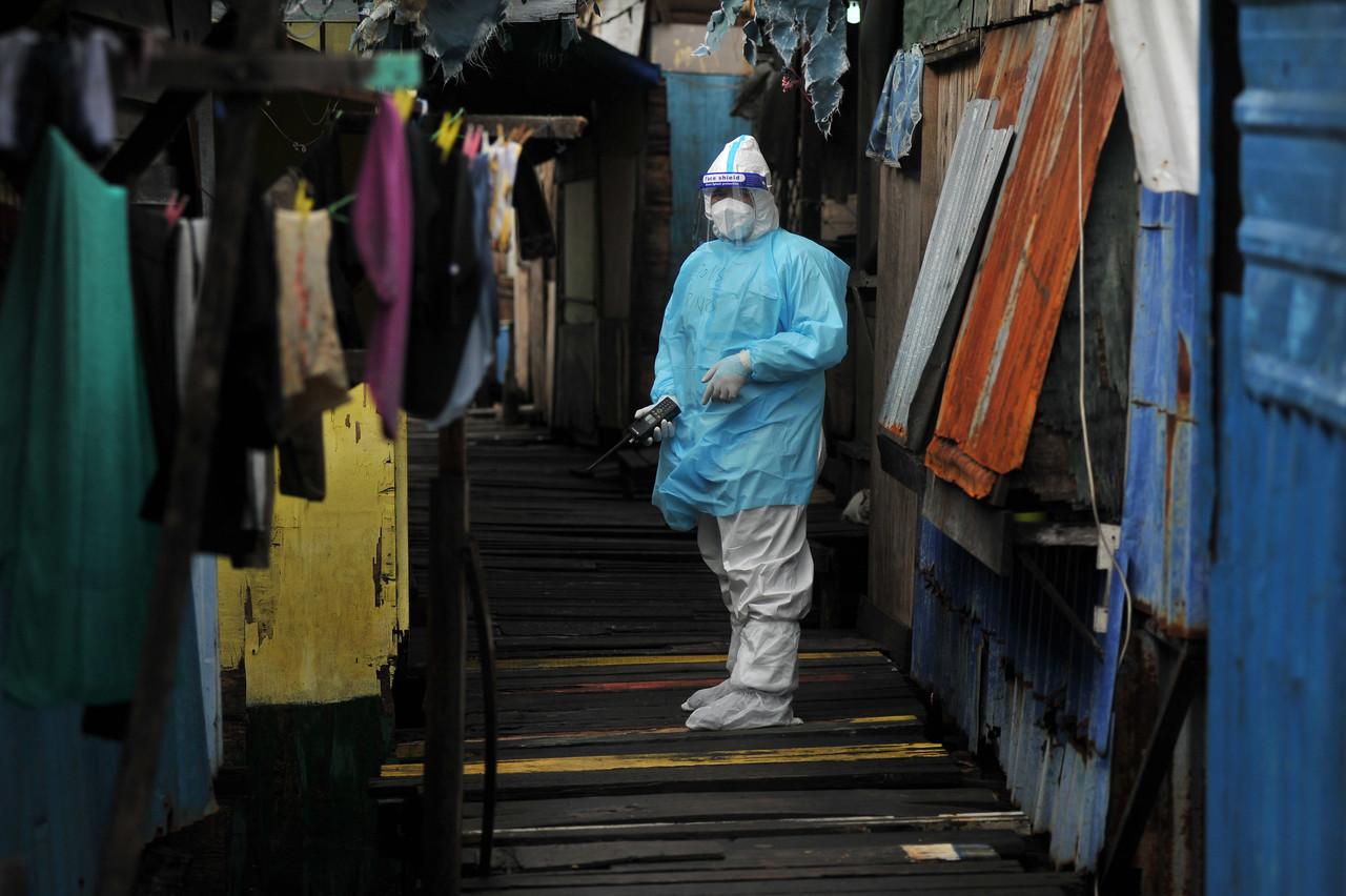A police officer wearing personal protective equipment patrols the water village of Saguking in Labuan where hundreds of villagers have been put under home quarantine following a spike in positive cases. Photo: Bernama